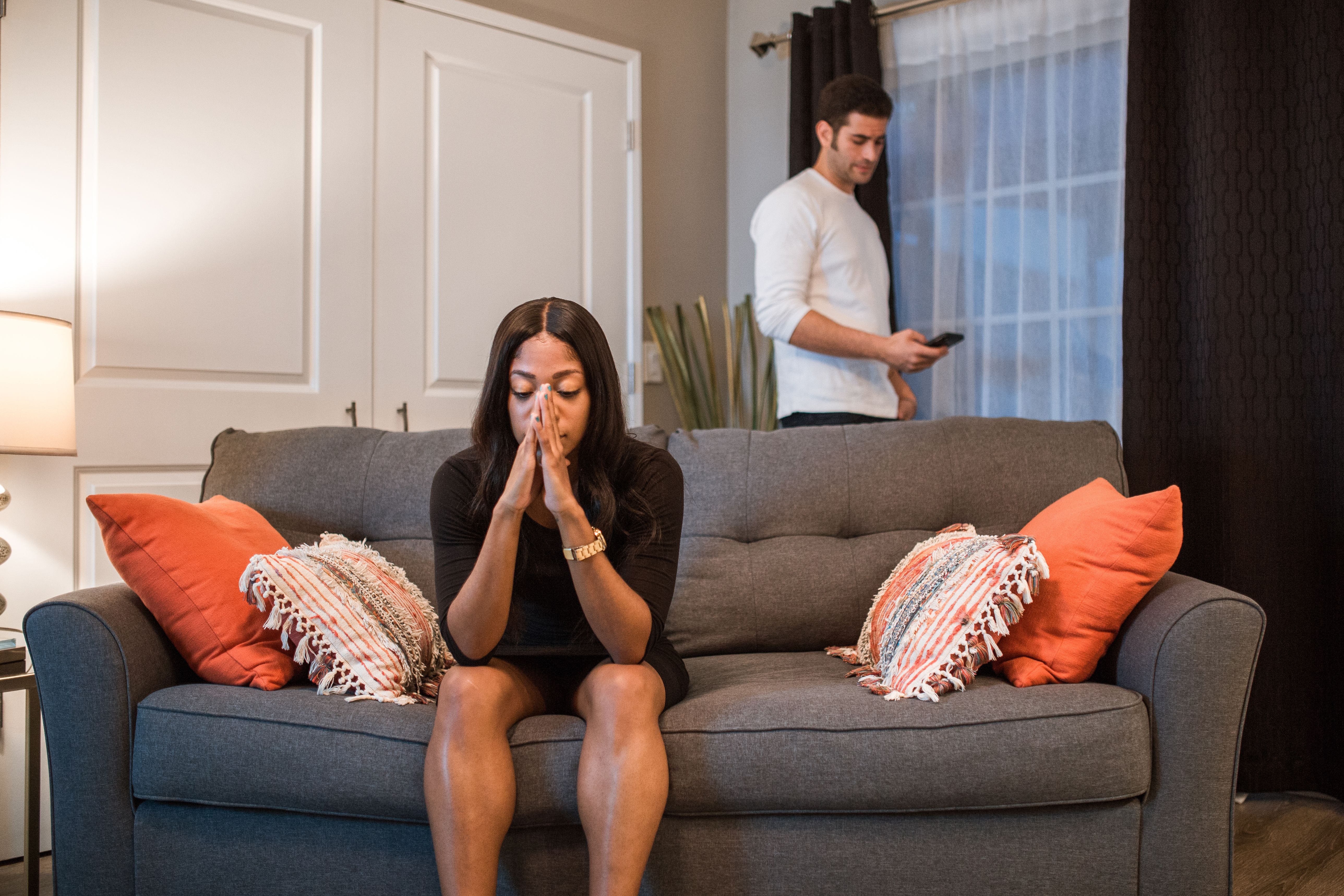 A man and woman experience emotional turmoil and separation in a living room, reflecting a disconnect in modern relationships.