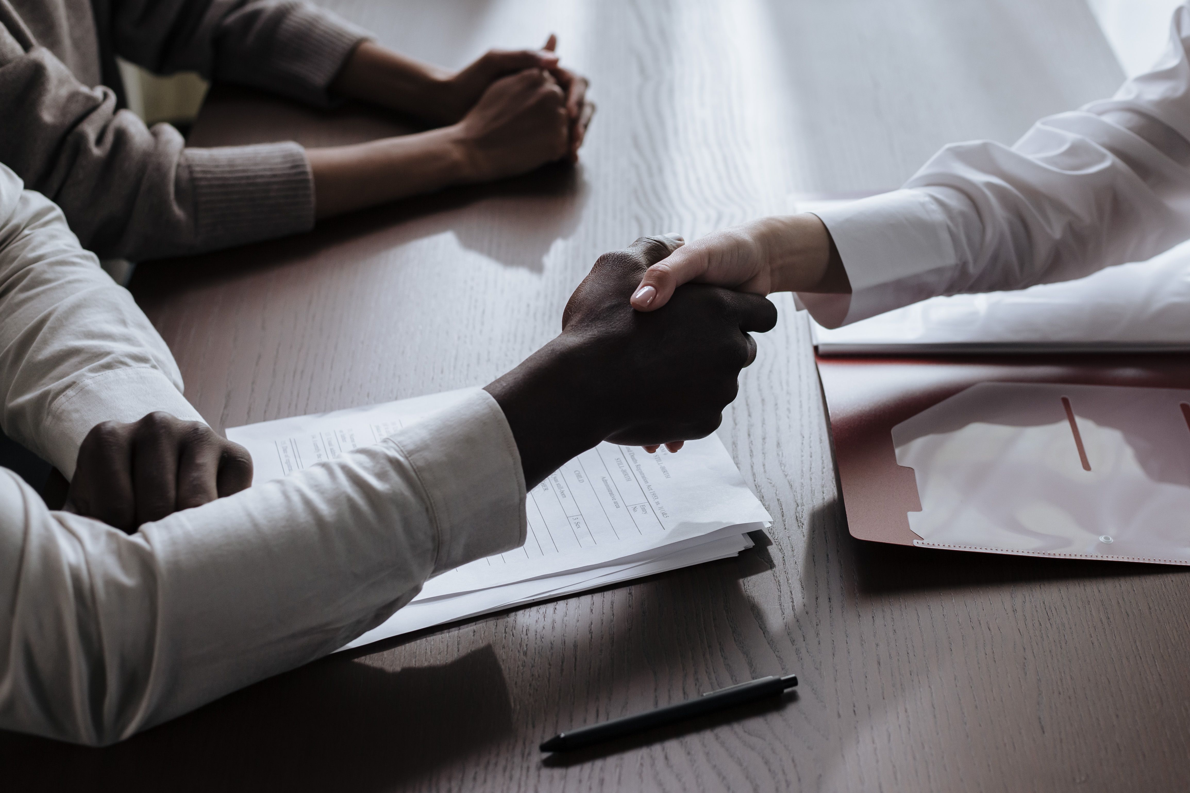 Handshake over contract documents marking a settlement in a large civil claims case